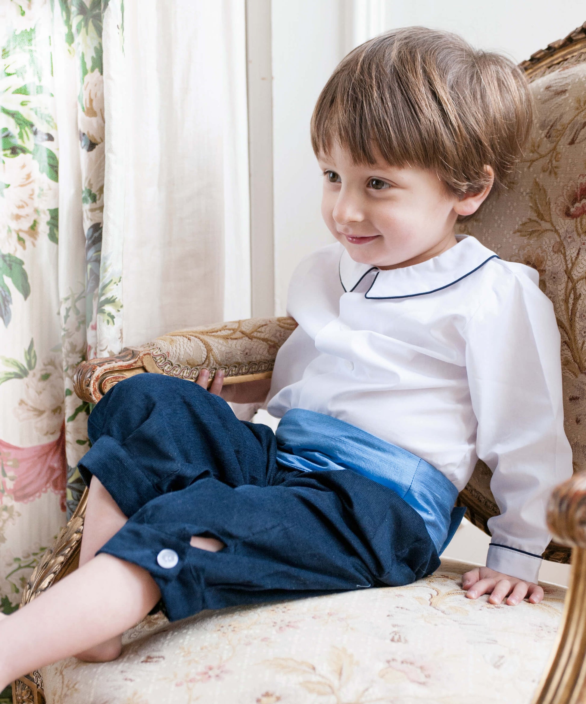 Pageboy wears white peter pan collar shirt, navy knickerbockers and blue silk cummerbund